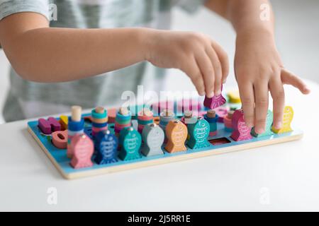 Umweltfreundliches Spielzeug für die Entwicklung. Nahaufnahme eines kleinen Kindes, das mit Holzfischen spielt und bunte Figuren zählt Stockfoto