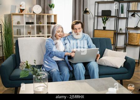 Glückliches Seniorenpaar, glücklicher Ehemann überglücklich Frau, die auf den Laptop-Bildschirm schaut, freut sich über fantastische Neuigkeiten. Konzept der Online-Lotterie gewinnen große kommerzielle Angebot Ruhestand und Freizeit. Stockfoto