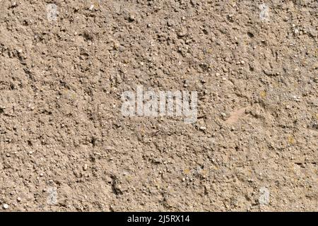 Wand Putz Hintergrund Textur. Abstrakte Kulisse aus Beton und kleinen Steinen. Braune Wand eines Gebäudes in Deutschland. Verwitterte Wandoberfläche. Stockfoto