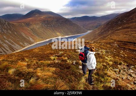 Ein paar Wanderer, die den Ben Crom Stausee in den Bergen von Mourne, County Down, Nordirland, betrachten Stockfoto