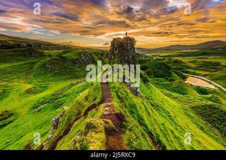 Sonnenuntergang auf der Isle of Skye im Sommer mit Castle Ewen Rock und einer Silhouette einer Person an der Spitze. Landschaft in Schottland am Abend mit Wolken Stockfoto