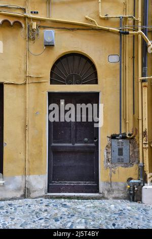 Detail des Äußeren eines alten Hauses mit einer Holztür und einem Gaszähler in der Wand, Sanremo, Imperia, Ligurien, Italien Stockfoto