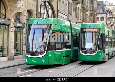 Basel, Schweiz - April 2022: Elektrische Straßenbahnen fahren aneinander vorbei. Die Stadt verfügt über ein ausgedehntes Straßenbahnnetz Stockfoto