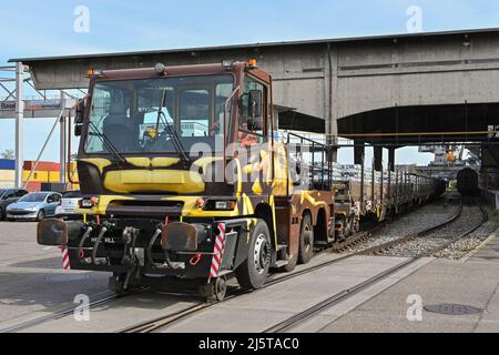 Basel, Schweiz - April 2022: Spezialfahrzeug für die Straßenbahn, das im Rheinhafen der Stadt einen schweren Zug mit Metallbarren abschotten soll Stockfoto