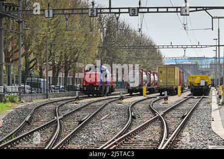 Basel, Schweiz - April 2022: Diesel-Rangierlokomotive und Güterwagen auf Gleisen im Rheinhafen der Stadt Stockfoto