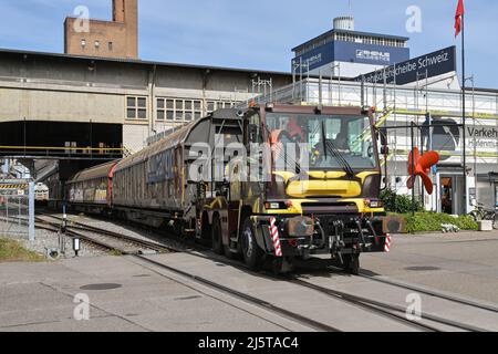 Basel, Schweiz - April 2022: Spezialfahrzeug für die Straßenbahn, das im Rheinhafen der Stadt einen schweren Güterzug shunt Stockfoto