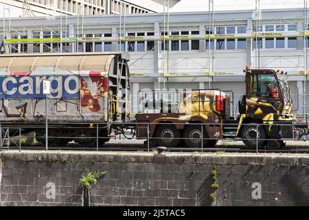 Basel, Schweiz - April 2022: Spezialfahrzeug für die Straßenbahn, das im Rheinhafen der Stadt einen schweren Güterzug shunt Stockfoto