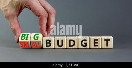 Großes oder kleines Budgetsymbol. Geschäftsmann dreht Holzwürfel und ändert Wörter kleines Budget zu großes Budget. Schöne graue Tabelle grauen Hintergrund, Kopie sp Stockfoto