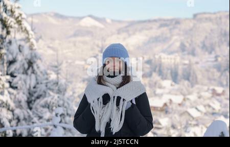 Glückliche Frau in gestricktem Schal und steht auf verschneiten Blick auf die Stadt in der Ukraine Stockfoto