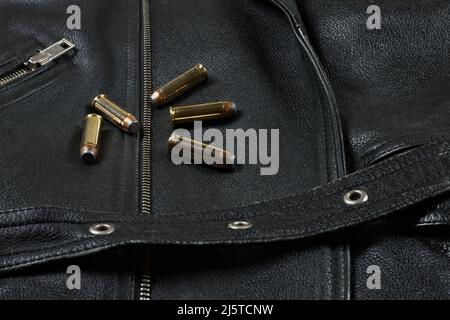 Fünf .44 Magnum Revolver Patronen liegen auf schwarzem Lederhintergrund (Biker-Jacke) Stockfoto