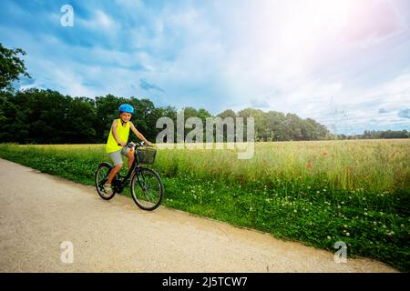 Kleiner Junge fährt Fahrrad im Park in der Nähe von Feld Stockfoto