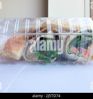 Klare Plastikreste-Behälter mit einem Huhn und Hummus-Wrap nach einer Mahlzeit im Restaurant übrig; verpackt oder verpackt zu Hause Lebensmittel zu nehmen. Stockfoto