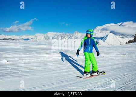 Kind geht auf dem Snowboard hoch in den Bergen bergab Stockfoto