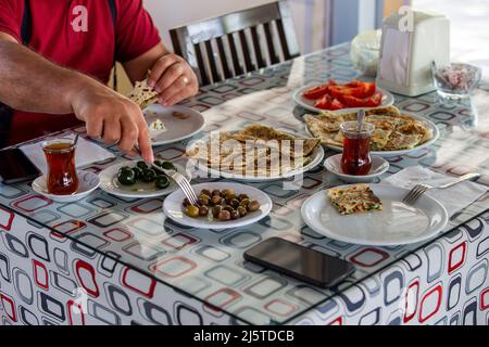 Der Mann, der am Frühstückstisch des Dorfes frühstückte. Verschiedene Frühstücksarten in der Türkei Stockfoto