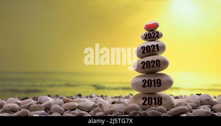 Das neue Jahr 2023 steht kurz bevor. Das neue Jahr 2023 beginnt. Jahre auf dem Steinturm geschrieben. Jahreszahlen von 2018 bis 2023. Sonnenuntergang im Hintergrund Stockfoto