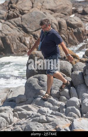 Westküste, Südafrika. 2022. Mann klettert über Felsen an einem Küstenort an der Westküste, Südafrika Stockfoto