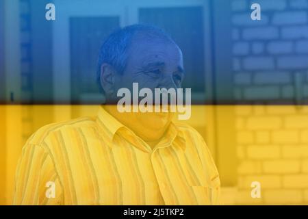 Porträt eines älteren Mannes im Freien. 70s Jahre alter lateinischer oder hispanischer Mann, der am Sommertag draußen steht. Casual und Lifestyle-Konzept. Ukrainische Flagge. Stockfoto