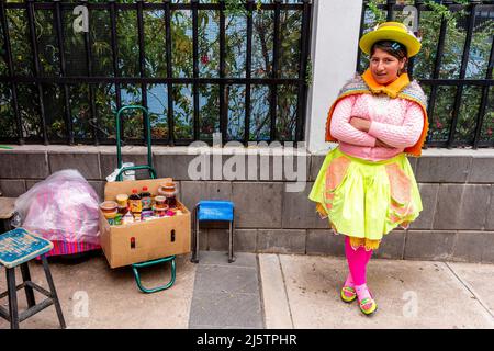 Eine junge Frau in traditionellem Kostüm, die Honig auf den Straßen von Puno, Provinz Puno, Peru verkauft. Stockfoto