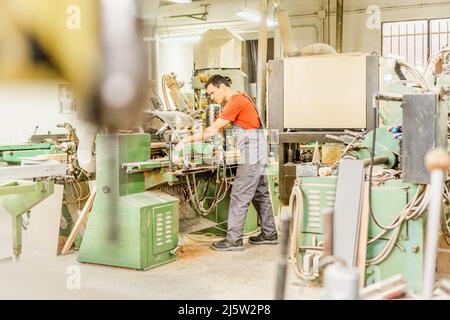 Konzentrierter Zimmermann, der in der Werkstatt an Geräten arbeitet Stockfoto