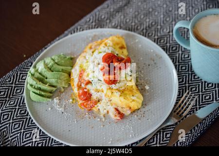 Teller mit hausgemachtem Frühstück: Omelette mit Käse und Tomaten. Stockfoto