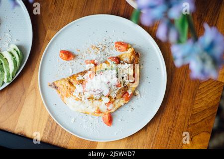 Teller mit hausgemachtem Frühstück: Omelette mit Käse und Tomaten. Stockfoto