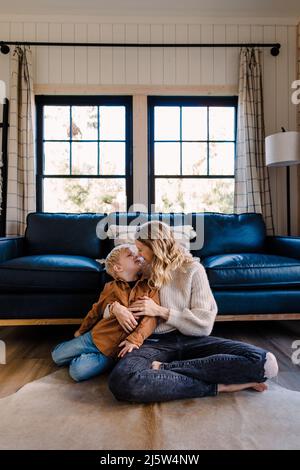 Kaukasische Mutter kuschelt sich mit dem Sohn in einer gemütlichen Hütte Stockfoto