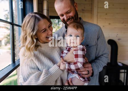 Kaukasische Eltern halten und lächeln bei der Babytochter in der Kabine Stockfoto