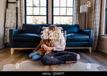 Weiße Mutter im mittleren Alter küsst Sohn auf der Seite des Kopfes im Studio Stockfoto