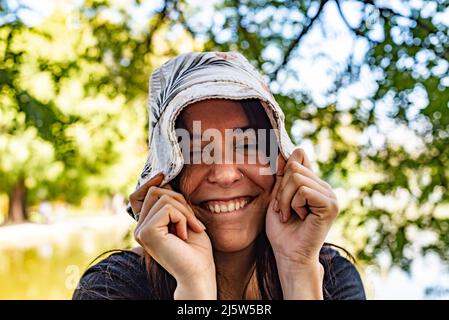 Junge verspielte Frau, die ihren Hut herunterzieht Stockfoto