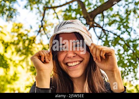 Junge verspielte Frau, die ihren Hut herunterzieht Stockfoto