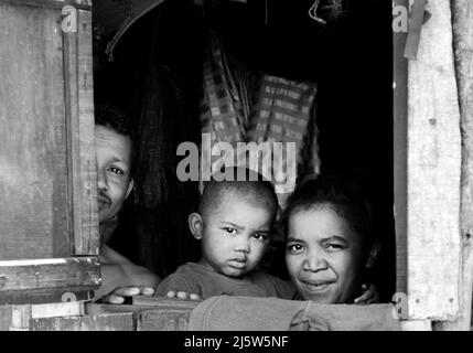 Eine madagassische Familie blickt aus ihrem Heimatfenster. Ambohimanga Region, Madagaskar. Stockfoto