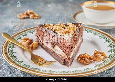 Schokoladenkuchen mit Birnen und Walnüssen auf dem Teller mit einer Tasse Kaffee Stockfoto