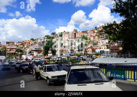 Autos und Menschen auf dem MDRM-Platz - die Steinsäule mit einer Madagaskar-Karte markiert den Aufstand von 1947. Antananarivo, Madagaskar. Stockfoto