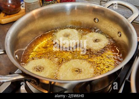 Kochen von Apfelpfannkuchen. Apfeldonut in kochendem Öl Stockfoto