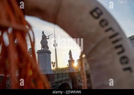 Berlin, Deutschland. 26. April 2022. Sonnenaufgang mit Blick auf den Fernsehturm, fotografiert durch einen Rettungsring an der Spree. Quelle: Jörg Carstensen/dpa/Alamy Live News Stockfoto