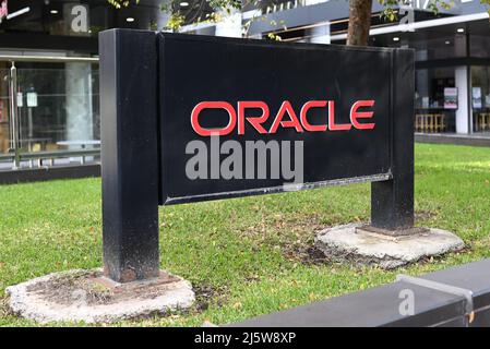 Schwarzes Schild der Oracle Corporation, mit rotem Schriftzug, typisch für das Firmenlogo, auf einem Grasfeld vor einem Bürogebäude Stockfoto