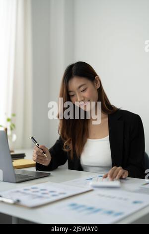 Portrait asiatische Buchhalterin Frau Hand drücken Sie auf Rechner für Finanzbericht oder Unternehmen Gewinn monatlich am Schreibtisch, Buchhalter Job und Arbeit aus Stockfoto
