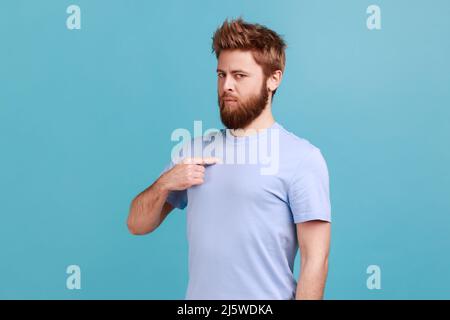 Das bin ich. Porträt eines selbstbewussten, narzisstischen bärtigen Mannes, der sich zeigt, sich selbstwichtig, stolz, berühmt fühlt. Innenaufnahme des Studios isoliert auf blauem Hintergrund. Stockfoto