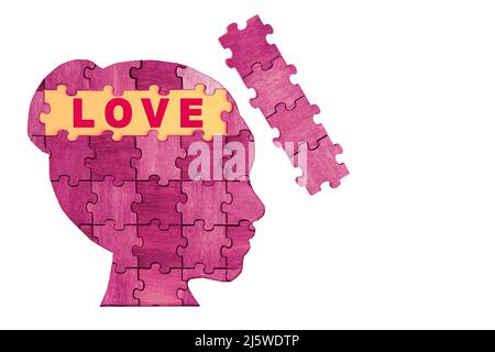 Wort LIEBE in einem weiblichen kopfförmigen Profil aus Holz Puzzle-Stücke isoliert auf weiß geschrieben. Romantische Liebe als Puzzle-Konzept. Stockfoto