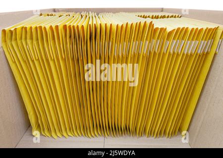 Stapel gelb gepolsterter Umschläge in einem Versandkarton. Qualitätskontrollkonzept. Stockfoto