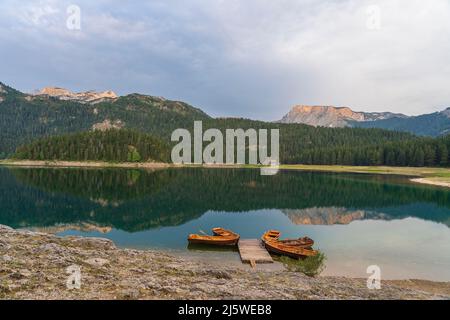 Blick auf den Schwarzen See oder Crno jezero, Nord-Montenegro. Touristenboote in der Nähe von Holzsteg am Schwarzen See im Durmitor Nationalpark in der Nähe von Zabljak, Euro Stockfoto