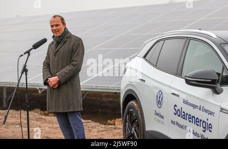 25. April 2022, Sachsen, Zwickau: Wolfram Günther (die Grünen), Sachsens Minister für Energie und Klimaschutz, spricht bei der Übergabe eines neuen Solarparks neben einem VW ID.4. Die Enerparc AG betreibt den sechs Hektar großen Solarpark Mosel und wird in den nächsten 20 Jahren jährlich 5,5 Millionen kWh Solarenergie für die Produktion der vollelektrischen Volkswagen-Modelle aus Zwickau liefern. Alle drei Volkswagen-Standorte in Sachsen werden bereits seit Ende 2017 mit Ökostrom aus Wasserkraft versorgt. Bisher kam dies jedoch aus Österreich. Zwickau ist nun der erste sächsische Standort, der neu ist Stockfoto