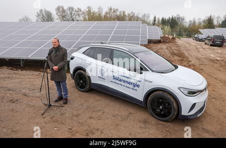 25. April 2022, Sachsen, Zwickau: Wolfram Günther (die Grünen), Sachsens Minister für Energie und Klimaschutz, spricht bei der Übergabe eines neuen Solarparks neben einem VW ID.4. Die Enerparc AG betreibt den sechs Hektar großen Solarpark Mosel und wird in den nächsten 20 Jahren jährlich 5,5 Millionen kWh Solarenergie für die Produktion der vollelektrischen Volkswagen-Modelle aus Zwickau liefern. Alle drei Volkswagen-Standorte in Sachsen werden bereits seit Ende 2017 mit Ökostrom aus Wasserkraft versorgt. Bisher kam dies jedoch aus Österreich. Zwickau ist nun der erste sächsische Standort Stockfoto