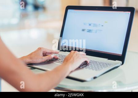 Nahaufnahme einer jungen Geschäftsfrau, die im weißen Büro am Laptop arbeitet. Stockfoto