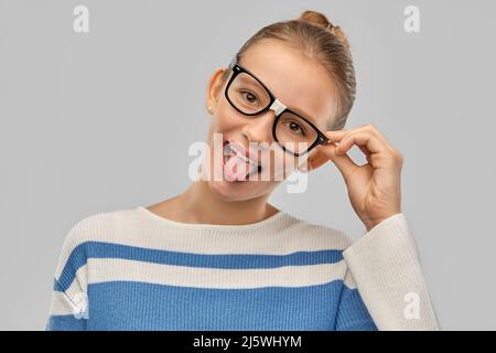 Teenage Student Mädchen in Brille zeigt Zunge Stockfoto