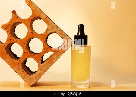 Stillleben der Flasche mit Pipette von feuchtigkeitsspendenden kosmetischen Serum neben rustikalen roten Ziegel mit Schreibraum Stockfoto