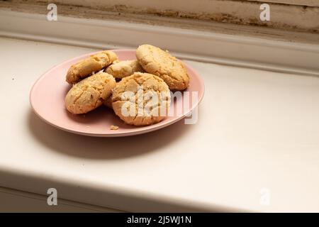 Rosafarbener Teller mit hausgemachten Plätzchen auf einem weißen antiken Herd Stockfoto