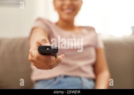Glückliche afroamerikanische Frau, die zu Hause Fernsehen schaut Stockfoto