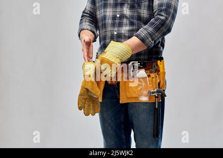 builder mit Arbeitswerkzeugen, die Handschuhe anziehen Stockfoto