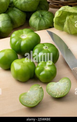 Frisches grünes Ganzes und halbierte mexikanische Tomatillo auf einem Schneidebrett Stockfoto